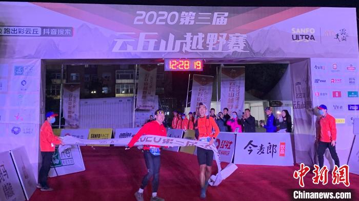 参加100公里越野赛的两名男子携手抵达终点。 刘小红 摄 参加100公里越野赛的两名男子携手抵达终点。 刘小红 摄