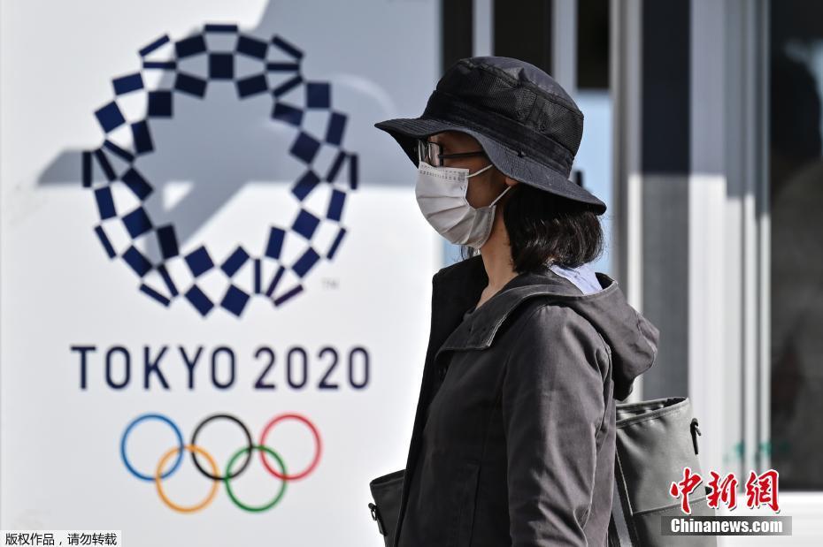 资料图:一名女士走过2020年东京奥运会海报。 资料图:一名女士走过2020年东京奥运会海报。