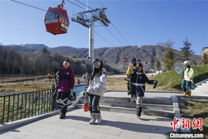 滑雪爱好者持雪板走向雪场 吕品 摄