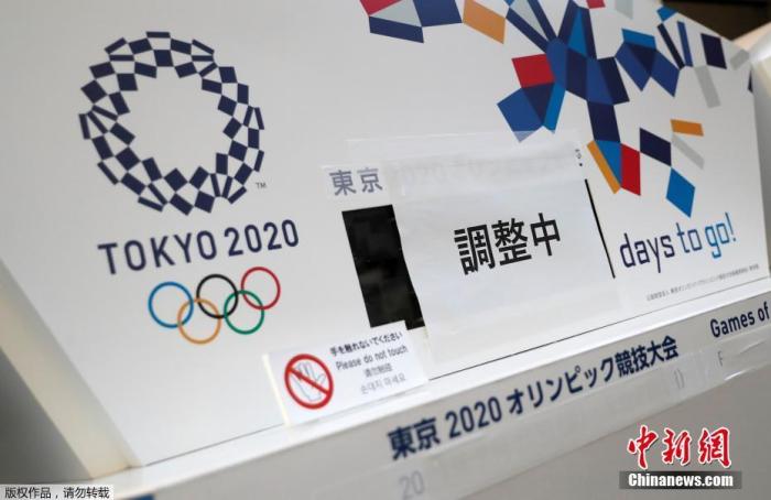 资料图：3月25日，在日本东京中央区，一间写字楼内的原本显示东京奥运会倒计时的电子屏被贴上了“正在调整”，下方奥运会的原定举办日期也被遮挡了起来。