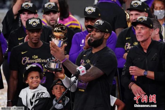 资料图：詹姆斯举起FMVP奖杯。