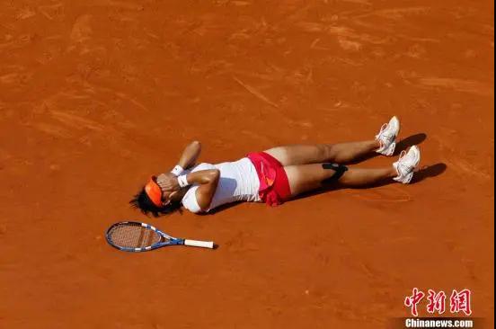 资料图：李娜2011年法网决赛取胜后，掩面躺在比赛场地上。