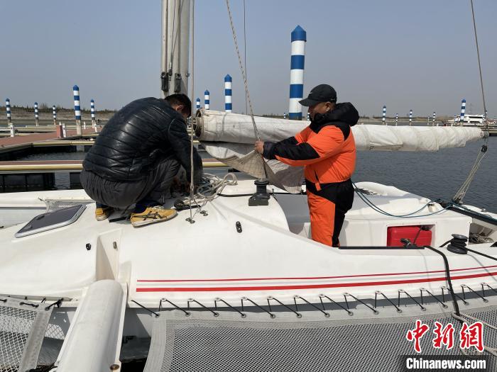 杨建新与助手在帆船上做航海出发前的准备工作。 白云水 摄 杨建新与助手在帆船上做航海出发前的准备工作。 白云水 摄