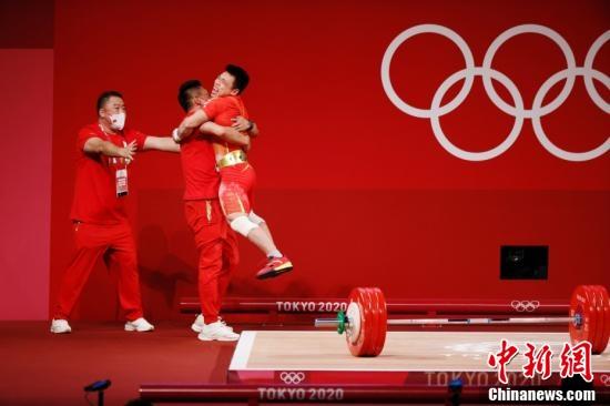 北京时间7月25日晚，在东京奥运会男子举重67公斤级比赛中，中国选手谌利军以抓举145公斤、挺举187公斤、总成绩332公斤夺冠。图为谌利军与教练庆祝胜利。 /p中新社记者 韩海丹 摄
