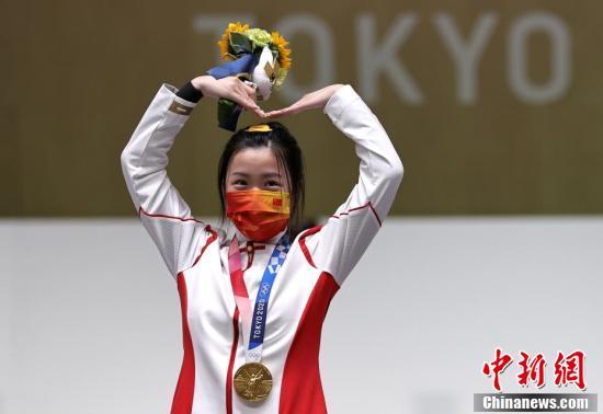 7月24日举行的东京奥运会女子10米气步枪决赛中，中国选手杨倩夺得冠军，为中国代表团揽入本届奥运会第一枚金牌。图为杨倩在领奖台上比出爱心手势。