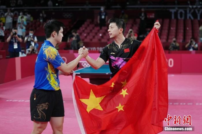7月30日晚，东京奥运会乒乓球男单决赛迎来中国选手“内战”。最终马龙以4：2战胜樊振东，成功卫冕冠军。这是中国代表团在本届奥运会的第19金。图为马龙与樊振东赛后举国旗致意。/p中新社记者 韩海丹 摄