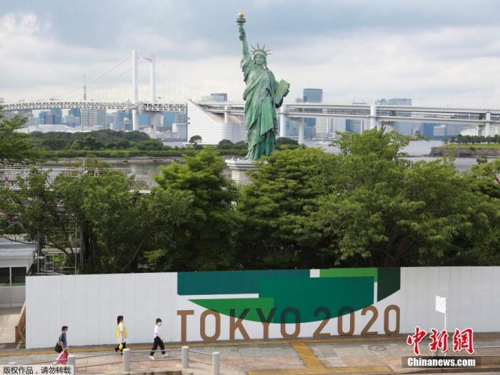 资料图:东京街头,人们走过2020东京奥运会宣传海报。 资料图:东京街头,人们走过2020东京奥运会宣传海报。