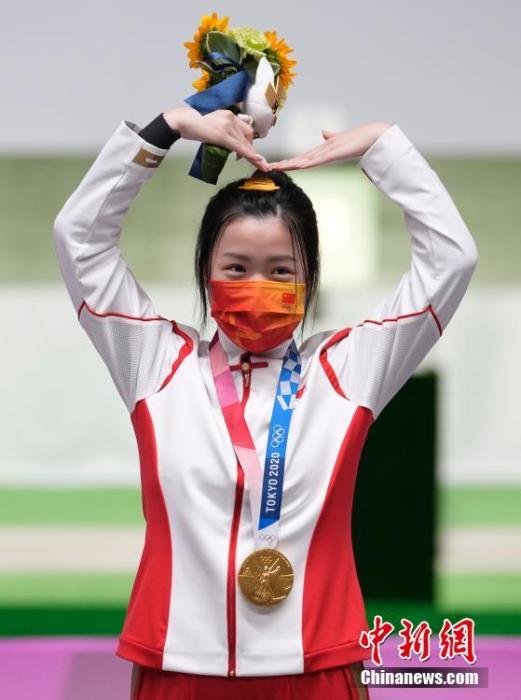 7月24日举行的东京奥运会女子10米气步枪决赛中，中国选手杨倩夺得冠军，为中国代表团揽入本届奥运会第一枚金牌。这也是本届东京奥运会诞生的首枚金牌。图为杨倩在领奖台上比出爱心手势。/p中新社记者 杜洋 摄