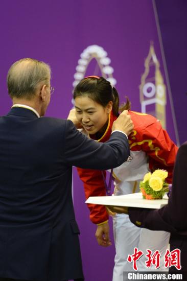 资料图：在伦敦奥运会女子10米气步枪决赛中，中国选手易思玲夺得本届奥运会首枚金牌。图为罗格为易思玲颁奖。图片来源：Osports全体育图片社 